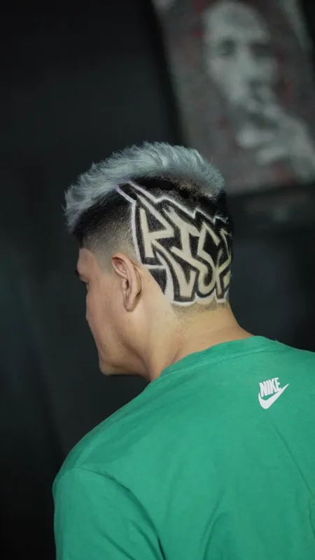 Cabello plateado y diseño geométrico oscuro en el lateral